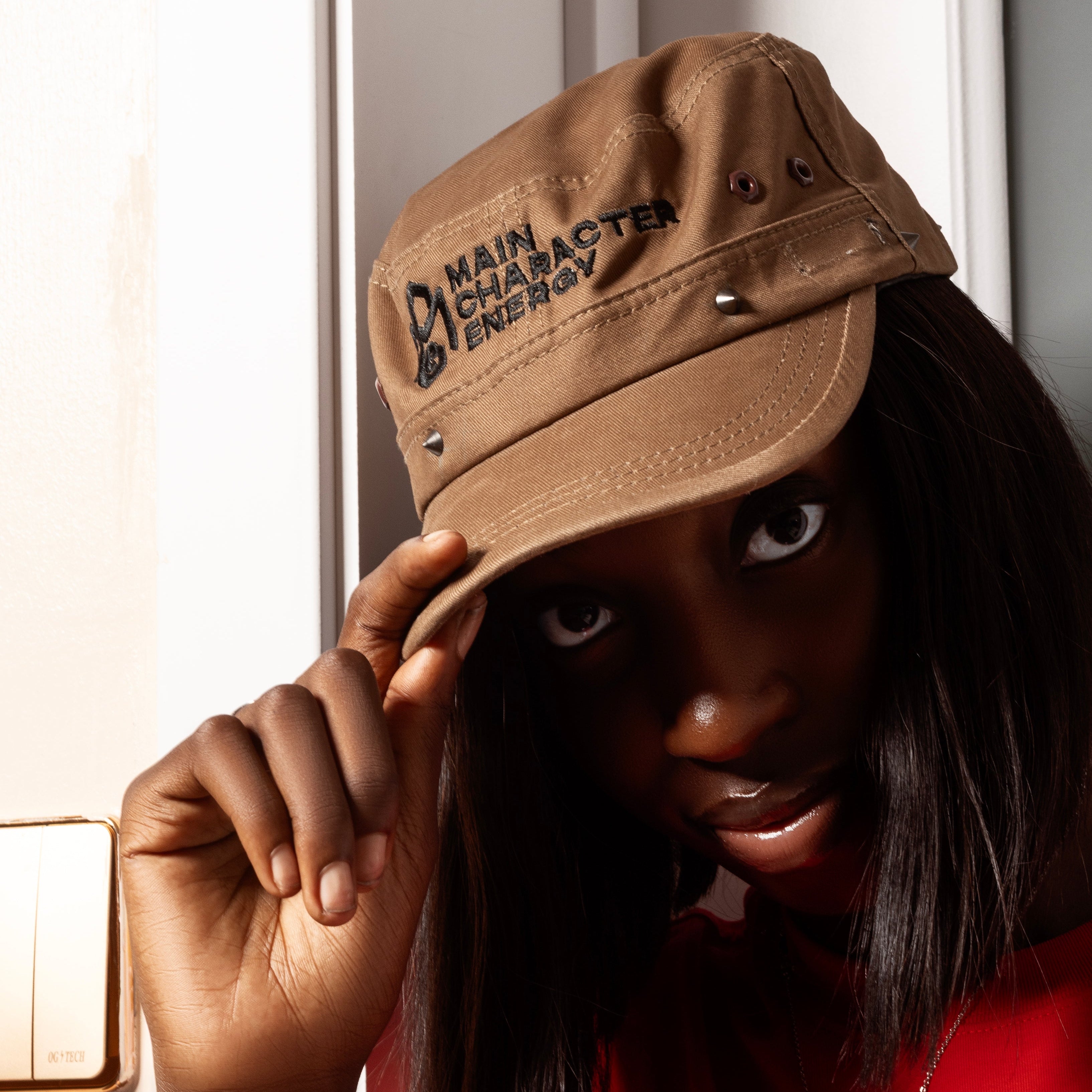Model wearing Militia La Tapa khaki cap with embroidered Main Character Energy logo