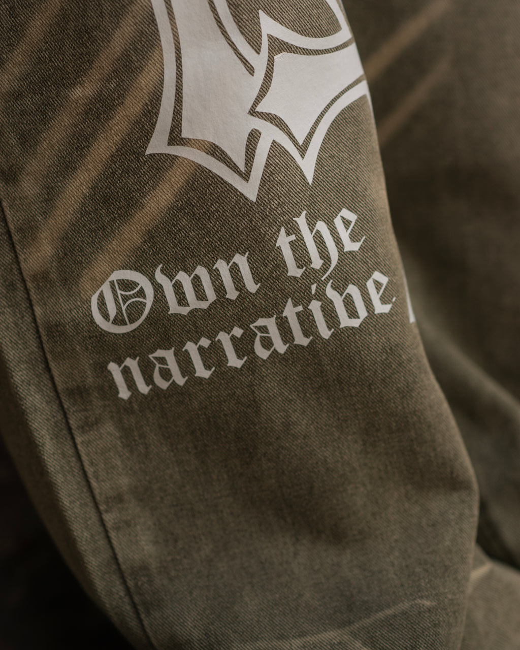 OTN Own The Narrative army green denim trousers with white cross design
